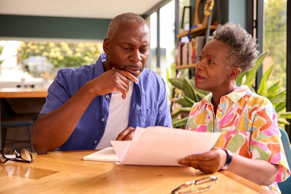 Senior Couple Sitting Around Table At Home Reviewing Finances Senior Couple Sitting Around Table At Home Reviewing Finances